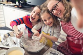 A mother with her two daughters making muffins and taking a selfie