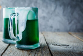 Green beer in mugs on rustic wood background, copy space