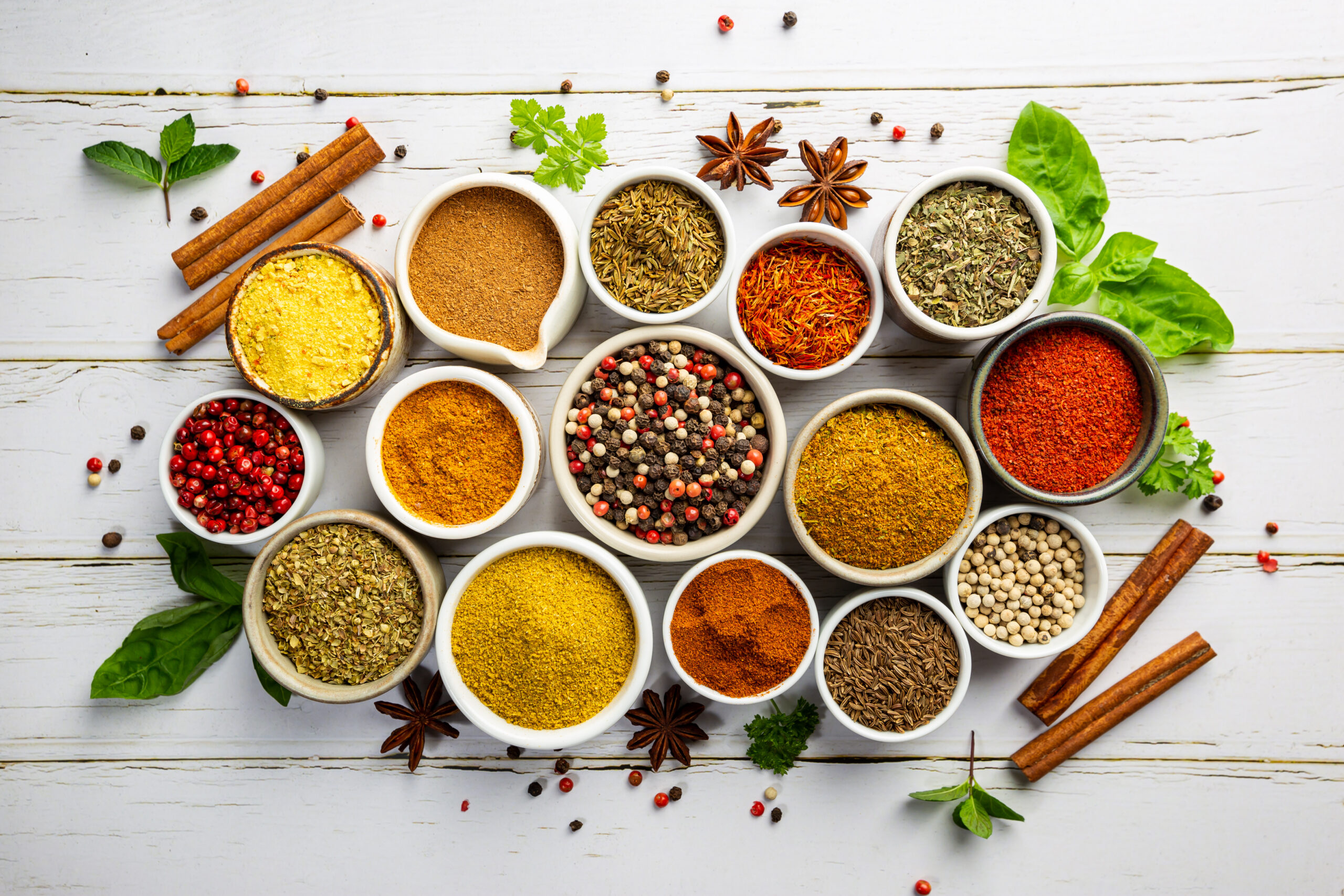 Herbs and spices in bowels over white wooden background. Top view with copy space